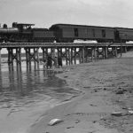 In late May of 1891, the Charlevoix Resort Association (Belvedere Club) lobbied to have the station built near them because the tracks passed over their property. By June 10 the matter was settled. “The North Side Gets the Plum” declared the Sentinel. The association was appeased because it was promised it would be getting its own small station. This shows the stairs and platform that were used temporarily between the end of June and late summer, 1892 before the building was completed. May 1891