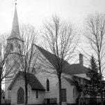 The first religious training classes in town were held in 1859 in second settlers John and Phoebe Dixon’s log cabin overlooking Pine Lake north of the upper channel. After 1867, Sunday School classes took place in a converted fish shanty near the channel. The first church structure, the Methodist Church on State Street, had its cornerstone laid on August 12, 1874 on property which its Ladies Aid Society had purchased the previous July for $65. The congregation built only as it obtained the funds and finished the imposing structure with this 100-foot spire in February of 1878. Methodist Church on State Street