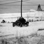 Winters used to be terribly long years ago. Ice could be found in Lake Michigan as late as May, in the early days delaying the shipping season when critical supplies needed to be brought in. But Charlevoix learned to cope, hunkering down when the big lake blasted its winds and snows across the town, often burying it, then shoveling out to enjoy the calm until the next onslaught. Here, a flivver strains to ascend the Grant Street hill at Lake Michigan Beach, with a patchwork blanket protecting the engine in place of a hood. Grant Hill