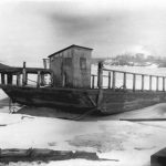 Two miles beyond Castle Farms, the Ironton Ferry across the South Arm of Lake Charlevoix has long been an integral part of the Charlevoix experience. Around 1878 this 18’ x 24’ cable-guided scow was built, capable of carrying one wagon and a team of horses. A hand-powered windlass operated by the captain, assisted by his passengers, held a half-inch cable that guided the craft. Here the vessel has been pulled ashore for the winter. In 1886, Charlevoix County bought the ferry and operated it toll free until 1949 Ironton Ferry