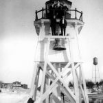 This photo, with Charlevoix in the background, was taken shortly after the lighthouse was moved from the North Pier to its present location on the South Pier. Photograph is property of the Charlevoix Historical Society.