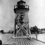 The wood lighthouse, known to the townspeople as “Old Reliable,” was moved to the south pier around, it is believed, 1911. The precise moving date and reason have never been discovered, nor the method of transfer. Before the move, in 1909 this fog signal bell had been suspended on a timber frame placed against the west side of the light. Its striking arm passed through a hole in the wall to a clock mechanism inside the “watch” room. The bell was struck twice, then twenty seconds of silence, one strike, another twenty seconds of silence, then the pattern repeated. “Old Reliable"