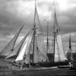 The schooner Porter dries her sails at the Clinton Street dock. At right, the billboard for Wizard Oil proclaims a popular cure-all of the era. The Charlevoix Sentinel of July 13, 1892 reported: “The famous Wizard Oil people are occupying the Lewis Grand Opera House every evening this week with a free entertainment embracing stereopticon views, songs, athletics, etc. While the entertainment is good and costs nothing, Wizard Oil is the ‘burden of their song.’ The schooner Porter