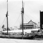 Some schooners even wintered here. The Sea Gem, whose home port was Charlevoix, rests next to the channel revetment beside the grist mill. She was built in Manitowoc, Wisconsin in 1863, and was often used for the transportation of grain to, and processed flour from, the mill. Above her bow appears the Fountain City House hotel. The Sea Gem was wrecked in a 1902 storm. The Sea Gem